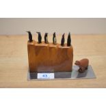 An Art Deco cocktail stick set, the bakelite holder containing six carved wooden penguin picks