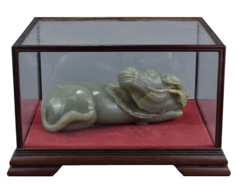A large Chinese celadon jade carving of a recumbent water buffalo. With a hardwood framed and glazed display box. Jade weight