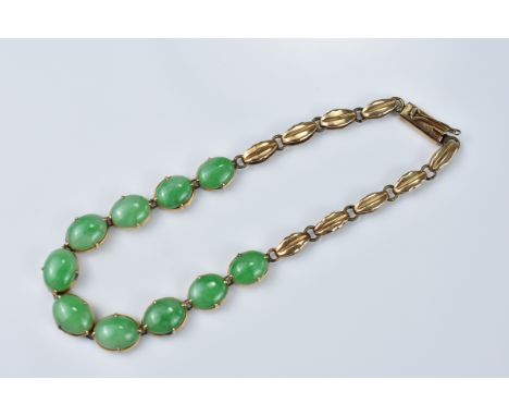 A yellow metal bracelet with ten jade stone cabochon inserts. Circa 1930's. Total length approx. 18.5cm. Cabochons approx. 7m