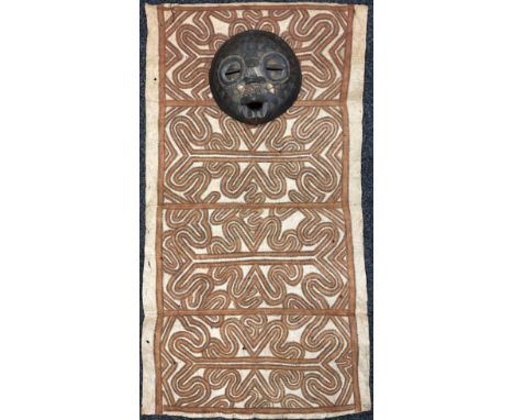 Tribal Art - a Papua New Guinea Tapa type cloth; a circular wall mask, inlaid with metal and beads, 28cm diameter (2) 