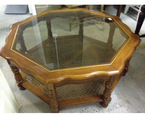 A large octagonal glass topped coffee table with cane shelf approx 108cm diameter.