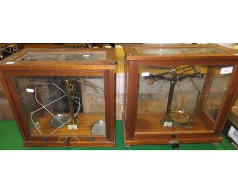 Two early 20th Century sets of scientific scales in glazed and wooden cases
