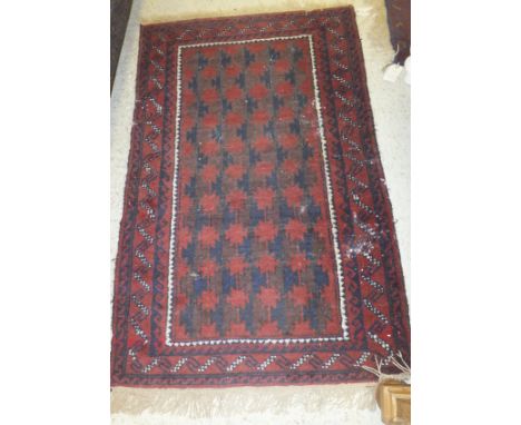 A Caucasian rug, the centre field with repeating medallions in dark blue and madder on a red ground within blue and red borde