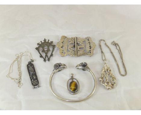 A collection of silver to include a nurse's belt buckle, ram's head torque style bangle, silver brooch, together with three v