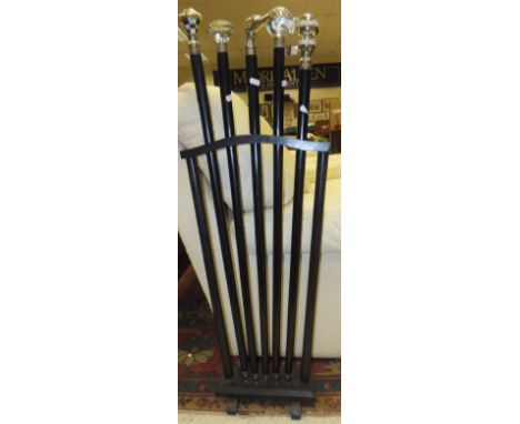 A modern black painted stick stand containing a set of five black tie / dress sticks