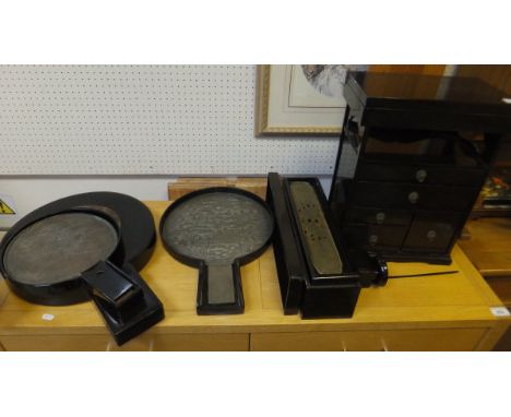 A Japanese lacquered table top cabinet, a Japanese lacquered box containing a brass panel, two Japanese embossed metal fans c