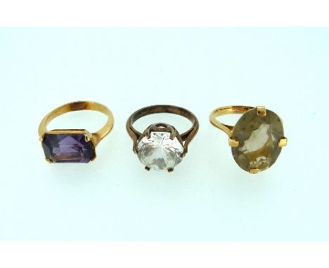 Three Rings, all mounted in gilt metal, one with an 'amethyst' coloured stone, one yellow quartz, and one white paste (3)