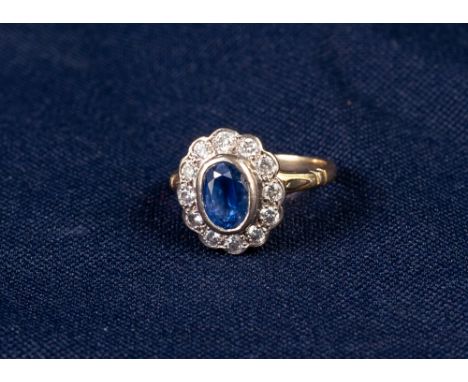 18ct GOLD, SAPPHIRE AND DIAMOND CLUSTER RING, collet set with an oval sapphire and surround of twelve round diamonds, 5.5gms,