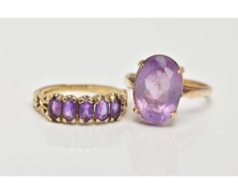 TWO 9CT GOLD AMETHYST RINGS, the first a five stone oval cut amethyst ring, prong set with scrolling shoulders and plain poli