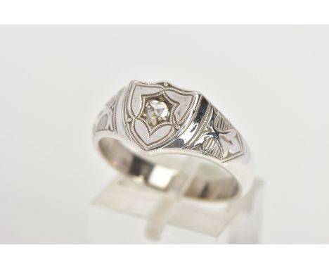 A DIAMOND SIGNET RING, the shield shape panel set with an old cut diamond, tapered shoulders and fleur de lis detailing, stam