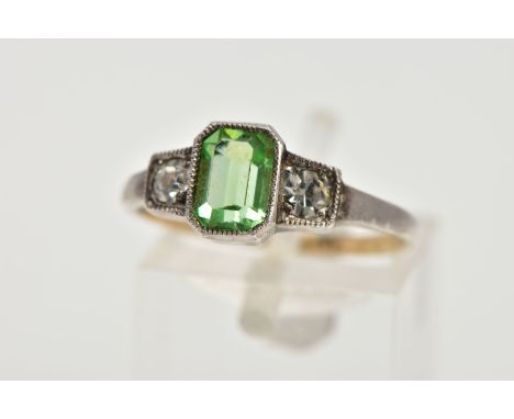 A GREEN PASTE RING, centring on an emerald cut green paste, flanked with two colourless circular cut paste, all in a white me