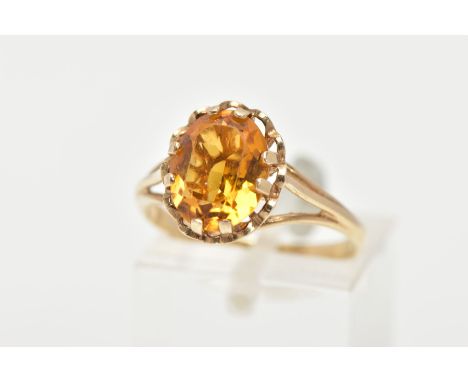 A 9CT GOLD CITRINE RING, an oval cut citrine prong set with a scallop surround and openwork gallery, trifurcated shoulders le