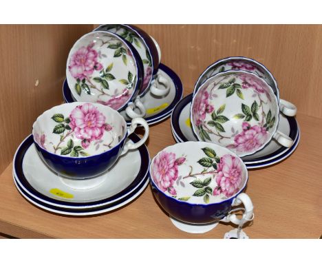 A SET OF SIX AYNSLEY ROSE PATTERN TEACUPS, the cups have a cobalt blue glaze to the exterior with white handles and feet, the