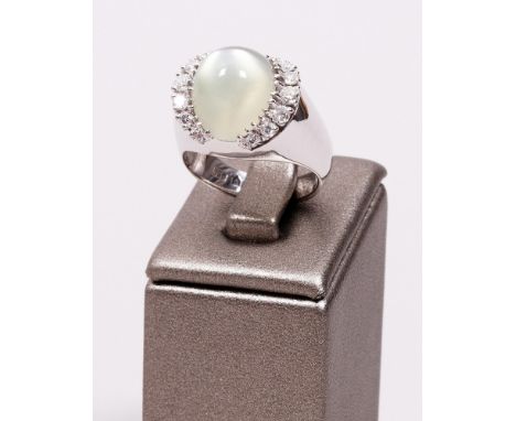 Entourage-Ring, 750er Weißgold, 1970er Jahre breite, gewölbte Ringschiene, besetzt mit Cabochon in gelb-grüner Farbe, umzogen