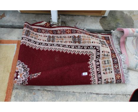 A VINTAGE RED PATTERNED FRINGED RUG 