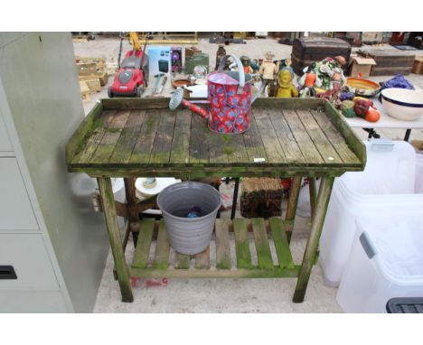A WOODEN POTTING BENCH, A WATERING CAN AND A PLANT POT 