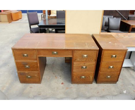 A MID TWENTIETH CENTURY OAK TWIN PEDESTAL DESK ENCLOSING SEVEN DRAWERS WITH BRASS HANDLES, 56" X 31", AND MATCHING THREE-DRAW