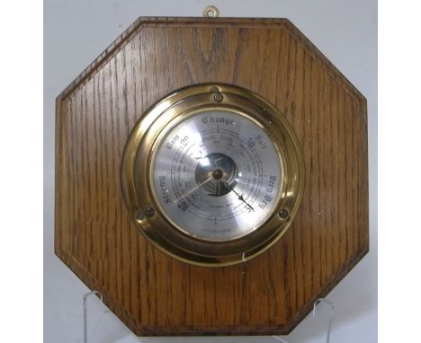 A brass ships barometer mounted on an oak octagonal base.
