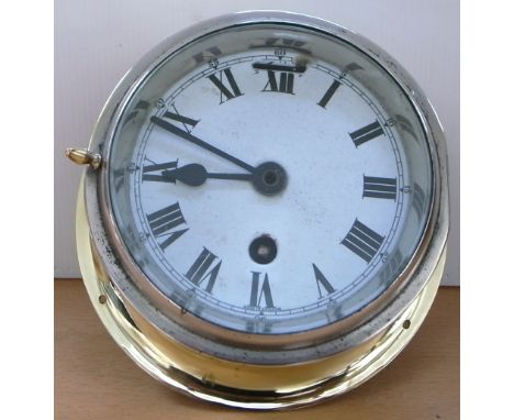 A brass cased ship's clock with white enamel dial set with Roman numerals inscribed “Made in England”, diameter 18cm.