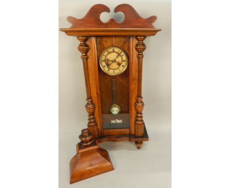 An early 20thC Vienna type wall clock, with turned pilasters and enamel type dial