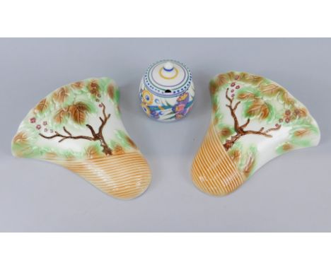 A pair of Sylvac wall pockets, decorated with trees and leaves and a Poole pottery preserve jar and cover, painted with flowe
