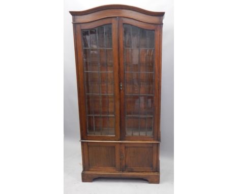 An early 20thC oak bookcase, with two leaded glazed doors, above two panelled doors, on bracket feet, 93cm wide.
