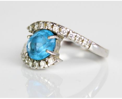 18ct white gold twist ring, the central oval cut blue topaz in claw setting, on diamond set twist shoulders and plain shank, 