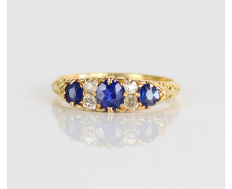 18ct yellow gold sapphire and diamond ring, the three graduated round cut sapphires separated by brilliant cut diamonds in cl