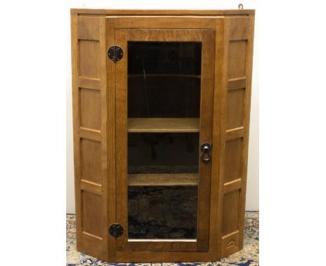 Robert "Mouseman" Thompson of Kilburn - an oak corner cabinet, glazed door enclosed by panelled canted angles, wrought metal 