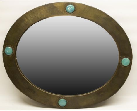 Liberty of London - a hammered brass oval mirror with nailed fold over rim, set with four Ruskin type blue roundels, with mak