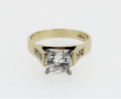 18ct yellow gold diamond solitaire ring, the round cut diamond in a white gold Tiffany style setting, on diamond set shoulder