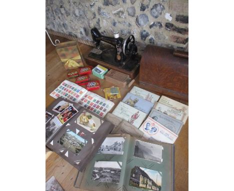 A 1920s Singer sewing machine with accessory box, vintage tins, collectors tea cards and albums, two postcard albums to conta