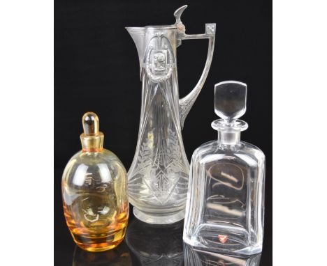 Three glass jugs and decanters comprising an Orrefors clear faceted decanter, an amber glass decanter and an etched and cut g