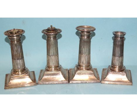 Three Edwardian short silver candlesticks with reeded columns, on square loaded bases with beaded edges, Sheffield 1902, make