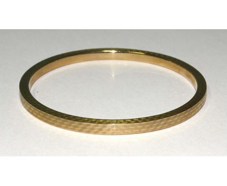 A 9ct gold slave bangle with engine-turned decoration, 78mm inner diameter, 10g.