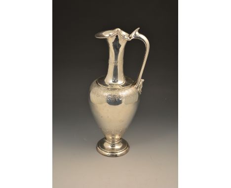 A Victorian silver ewer shape claret jug, by Edward Hutton, London 1884, with engraved bands and a grotesque mask head to the