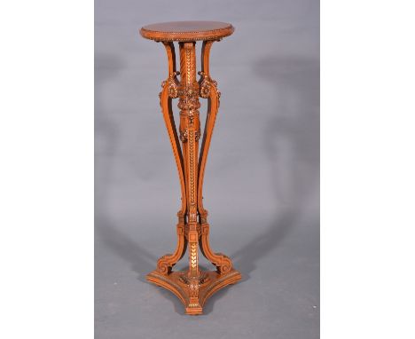 A George I style satin-walnut and parcel-gilt torchere, circular top with a beaded outline, spiral twist and fluted column wi