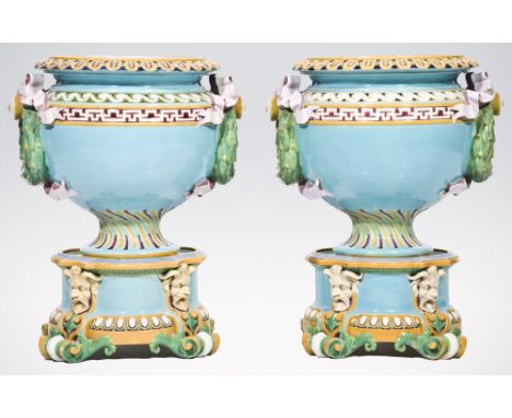 A pair of large Minton majolica jardinieres and stands, pedestal urn shape with moulded decorations, ribbon tie and laurel ha