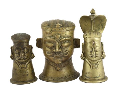 A group of three brass alloy Shiva Mukhalingam, Southern India, 16th-18th century, each depicting a Shiva head, wearing his c