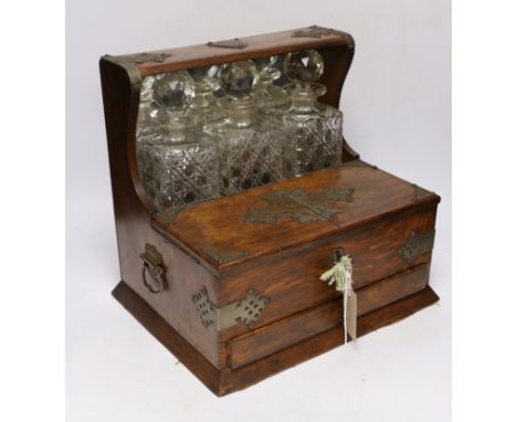 An oak tantalus/compendium containing three cut glass decanters, chess and draught sets, etc.
