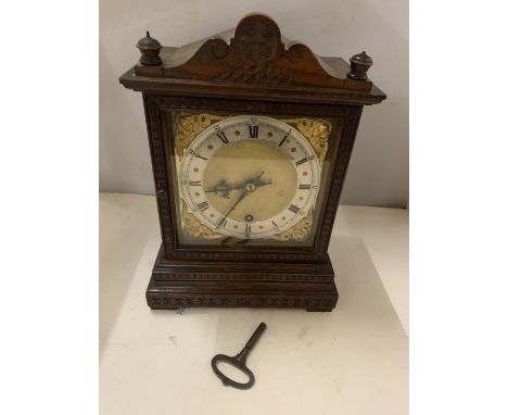 A DECORATIVE OAK CASED MANTLE CLOCK WITH GILT FACE AND ROMAN NUMERALS AND A KEY 