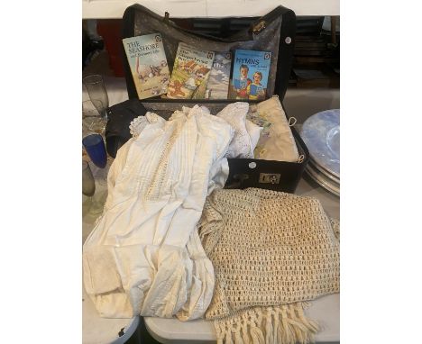 A SUITCASE CONTAINING VINTAGE CLOTHING, LINEN, BLANKET, LADYBIRD BOOKS, ETC 