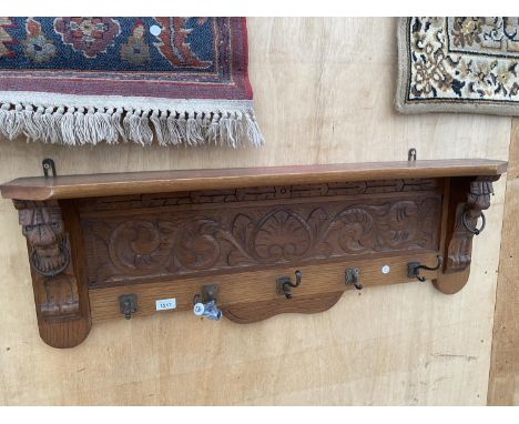 A WOODEN WALL SHELF WITH LOWER COAT HOOK SECTION WITH CARVED LION HEAD DETAIL 