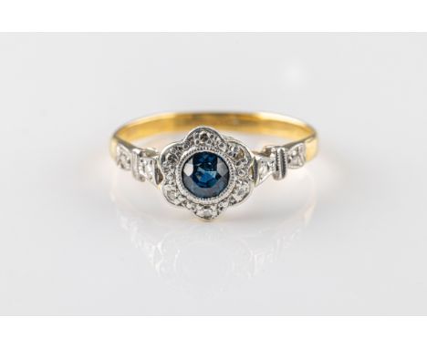  A sapphire and diamond ring in 18ct yellow gold and platinum, of foliate design centred on a bezel-set round-cut blue sapphi