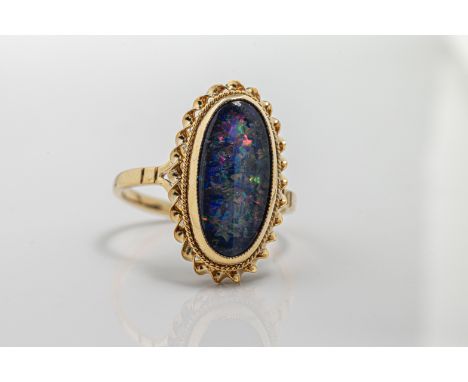  An opal ring set with an oval-shaped harlequin opal doublet, with decorative twist surround in 9ct yellow gold, ring size K.