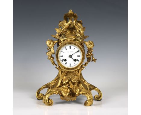  A 19th Century French ormolu mantel clock of scrolling foliate form, surmounted with floral swags and courting birds, signed