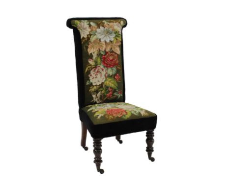  A Victorian prayer-style chair later upholstered in floral tapestry on scroll-shaped and turned legs with castors. 