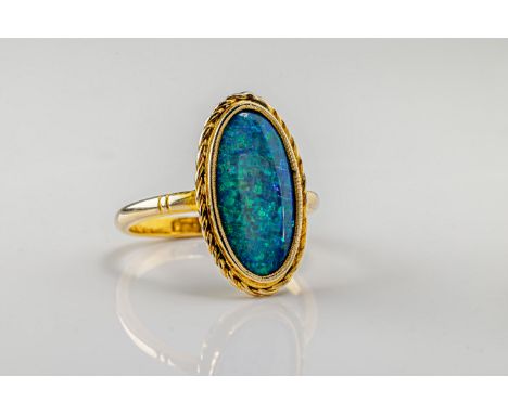  An opal ring in 9ct yellow gold, the oval cabochon opal doublet within a decorative gold surround, ring size O. 