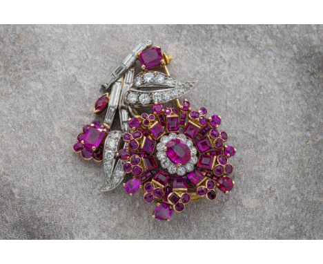  A ruby and diamond flowerhead brooch in white and yellow gold, the flowerhead set with a central oval-cut ruby with diamond 