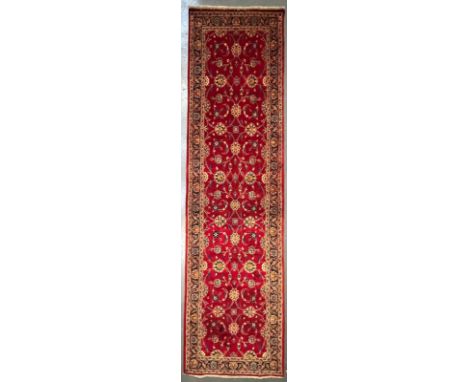 A 20th century Central Persian Islamic Kashan floor carpet runner rug. The runner having a central red ground panel with poly